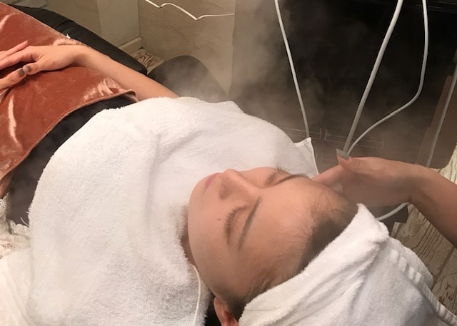 フェイシャルでスチームを当てられている女性